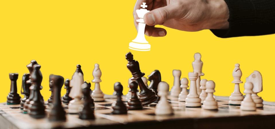 A hand placing a chess piece down on a chess board