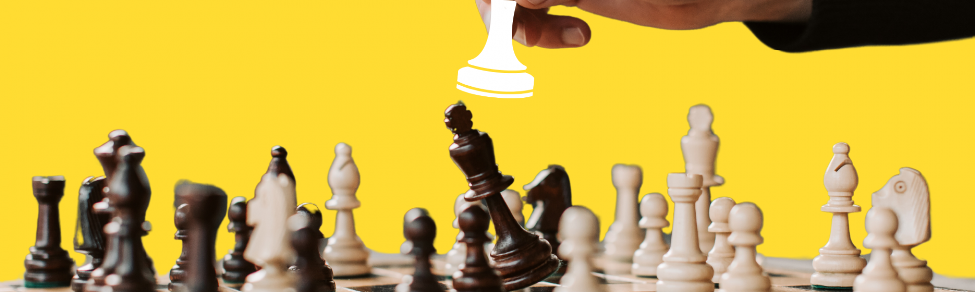 A hand placing a chess piece down on a chess board
